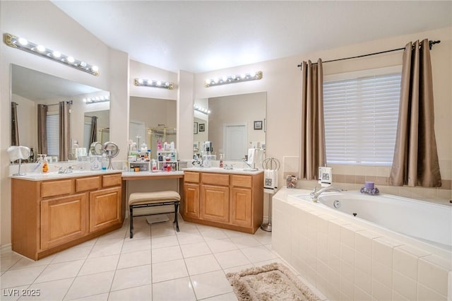 bathroom with tiled tub, vanity, and tile patterned flooring