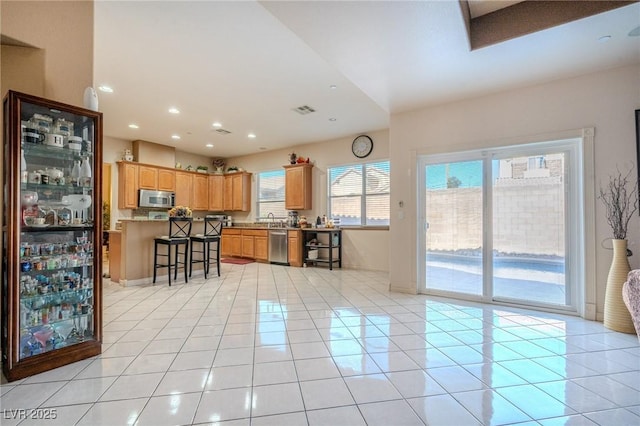 kitchen with appliances with stainless steel finishes, a kitchen island, a breakfast bar area, and light tile patterned floors