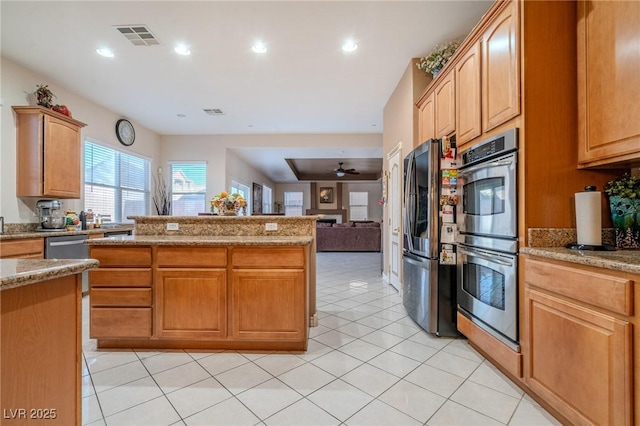 kitchen with light stone counters, light tile patterned floors, stainless steel appliances, and ceiling fan