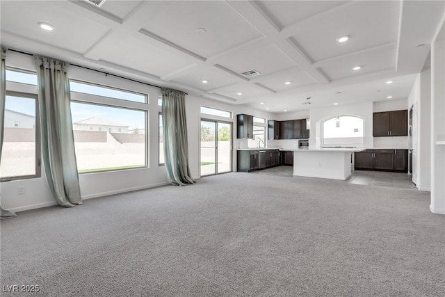 unfurnished living room with sink, coffered ceiling, light colored carpet, and beam ceiling