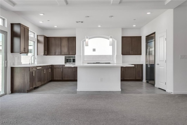 kitchen with backsplash, a center island, light colored carpet, dark brown cabinetry, and stainless steel appliances