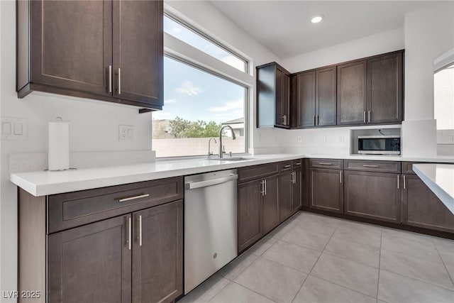 kitchen featuring light tile patterned flooring, appliances with stainless steel finishes, dark brown cabinets, and sink