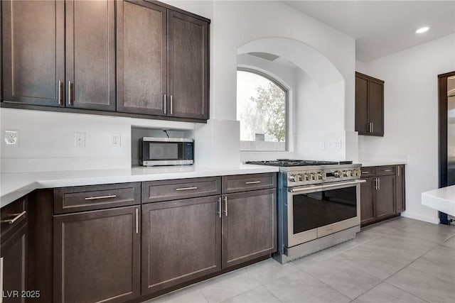 kitchen with appliances with stainless steel finishes, dark brown cabinets, and light tile patterned floors