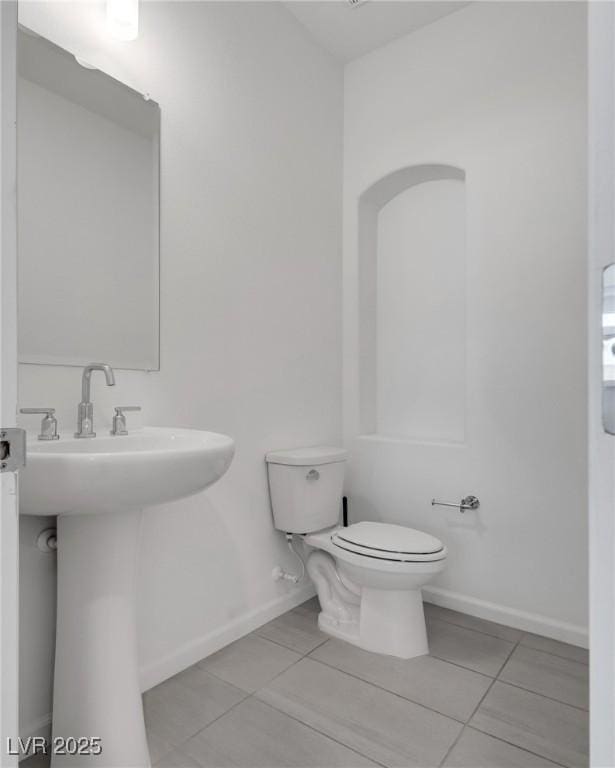 bathroom with sink, toilet, and tile patterned flooring