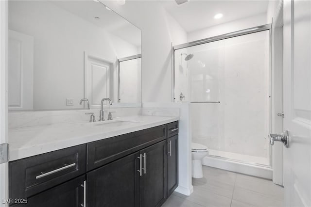 bathroom featuring tile patterned flooring, vanity, a shower with shower door, and toilet