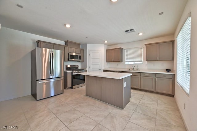 kitchen with a kitchen island, appliances with stainless steel finishes, sink, and light tile patterned floors