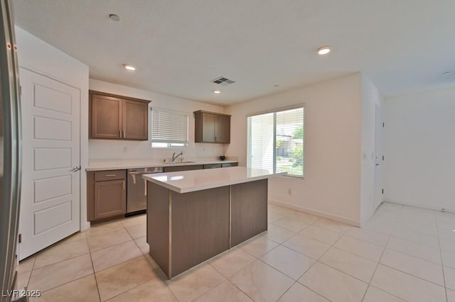 kitchen with sink, light tile patterned floors, dishwasher, and a kitchen island