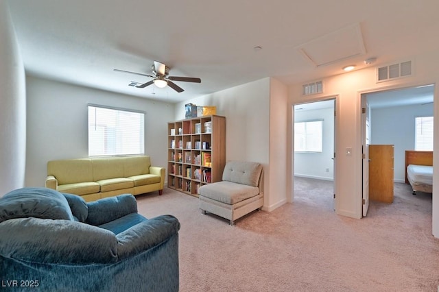 living area featuring a wealth of natural light, light colored carpet, and ceiling fan