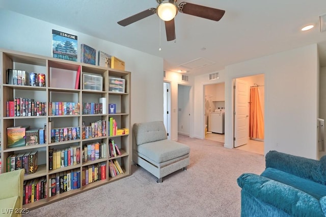 living area featuring light colored carpet and washer / dryer