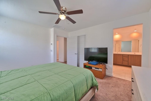 bedroom featuring light carpet, ensuite bath, and ceiling fan