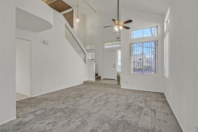 interior space featuring a high ceiling, light carpet, and ceiling fan