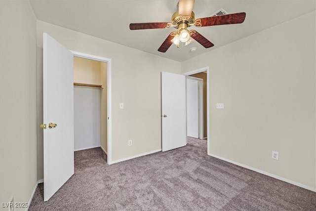 unfurnished bedroom with a walk in closet, light colored carpet, a closet, and ceiling fan