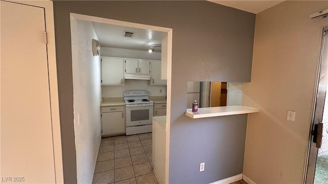 kitchen featuring stainless steel refrigerator, white cabinetry, white electric range oven, light tile patterned flooring, and kitchen peninsula