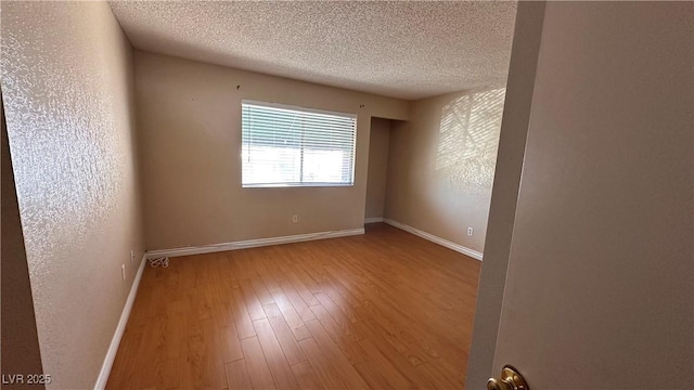 spare room with hardwood / wood-style floors and a textured ceiling