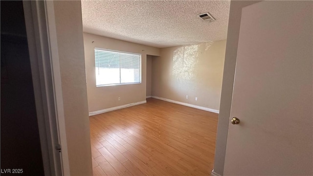 spare room featuring hardwood / wood-style floors and a textured ceiling