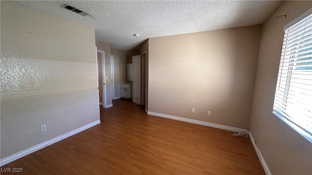 spare room featuring hardwood / wood-style floors and a textured ceiling