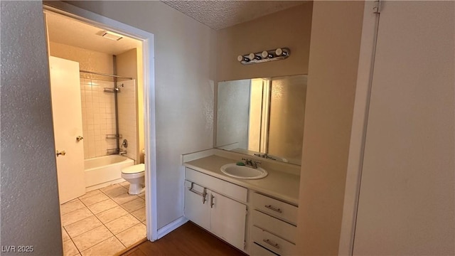 full bathroom with toilet, tiled shower / bath, a textured ceiling, vanity, and tile patterned flooring