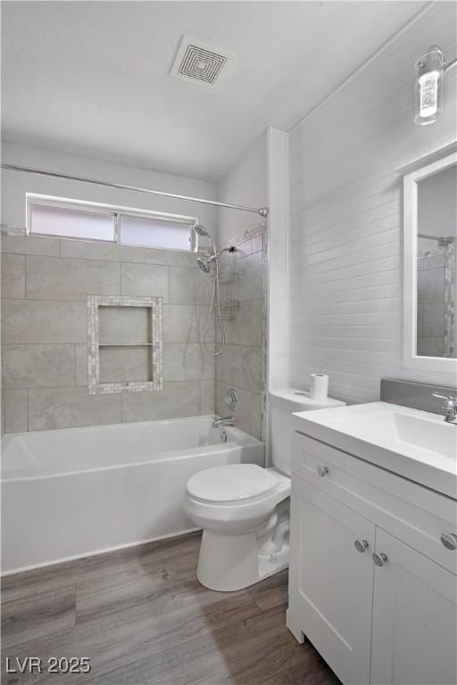 full bathroom with hardwood / wood-style flooring, vanity, tiled shower / bath combo, and toilet