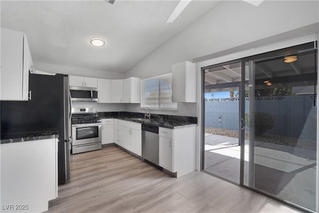 kitchen with sink, appliances with stainless steel finishes, white cabinets, vaulted ceiling, and light wood-type flooring