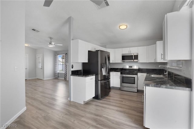 kitchen with sink, white cabinetry, appliances with stainless steel finishes, ceiling fan, and light hardwood / wood-style floors