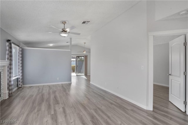 unfurnished living room with lofted ceiling, a textured ceiling, a fireplace, and light hardwood / wood-style flooring