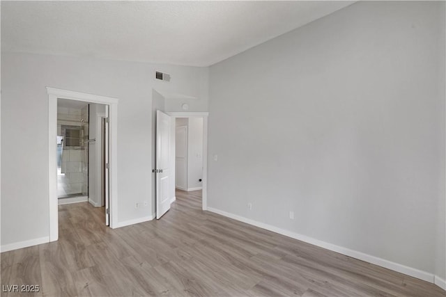 unfurnished bedroom with vaulted ceiling and light hardwood / wood-style flooring