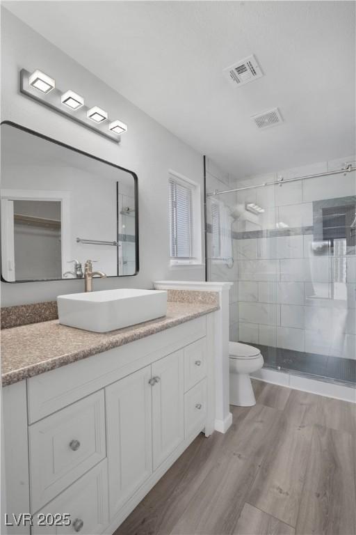 bathroom featuring vanity, toilet, an enclosed shower, and hardwood / wood-style floors