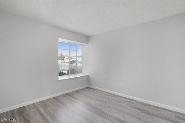 empty room with light hardwood / wood-style floors and a textured ceiling