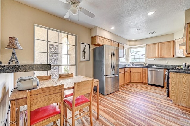 kitchen featuring sink, light brown cabinets, stainless steel appliances, light hardwood / wood-style floors, and wall chimney range hood