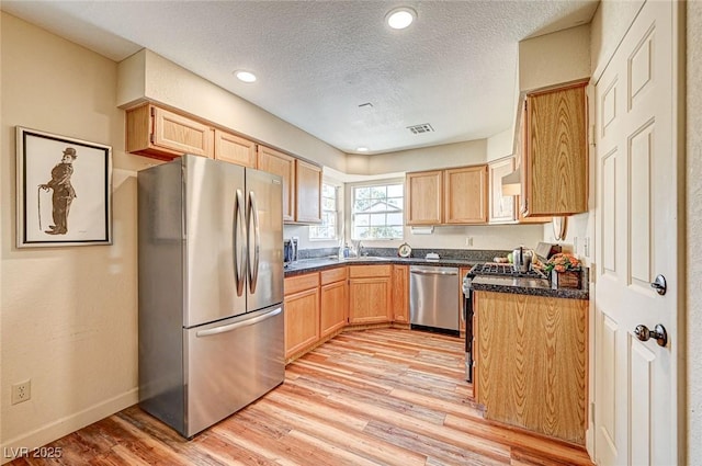 kitchen with appliances with stainless steel finishes, sink, light brown cabinetry, and light wood-type flooring