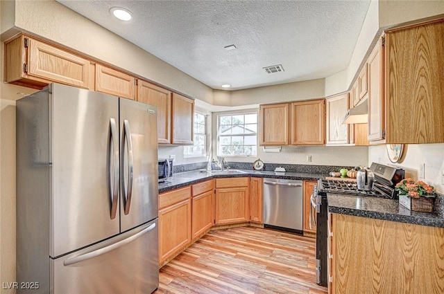 kitchen with sink, light hardwood / wood-style flooring, stainless steel appliances, a textured ceiling, and light brown cabinetry