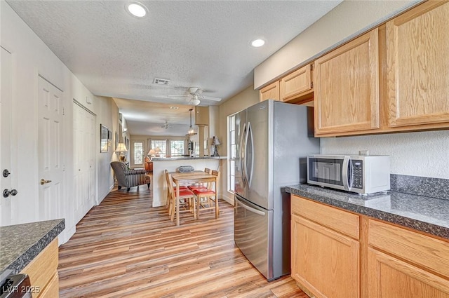 kitchen featuring appliances with stainless steel finishes, light brown cabinetry, ceiling fan, a textured ceiling, and light wood-type flooring