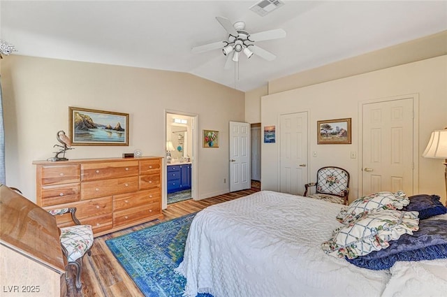 bedroom with vaulted ceiling, connected bathroom, ceiling fan, and light hardwood / wood-style floors