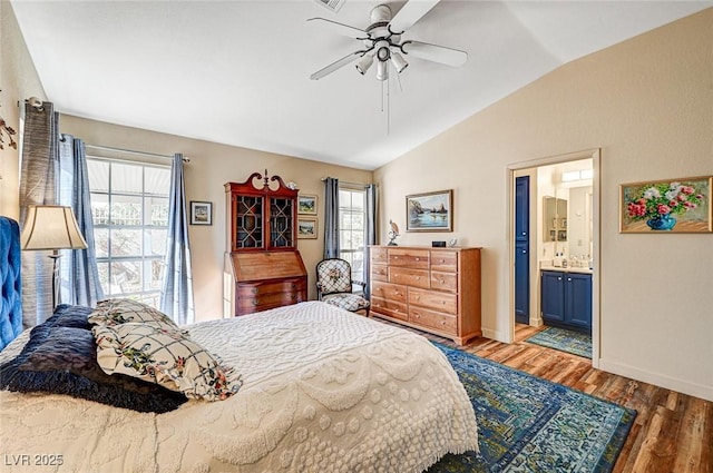 bedroom featuring lofted ceiling, multiple windows, wood-type flooring, and ensuite bath