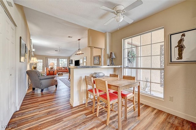 dining area with ceiling fan, lofted ceiling, light hardwood / wood-style flooring, and ornate columns