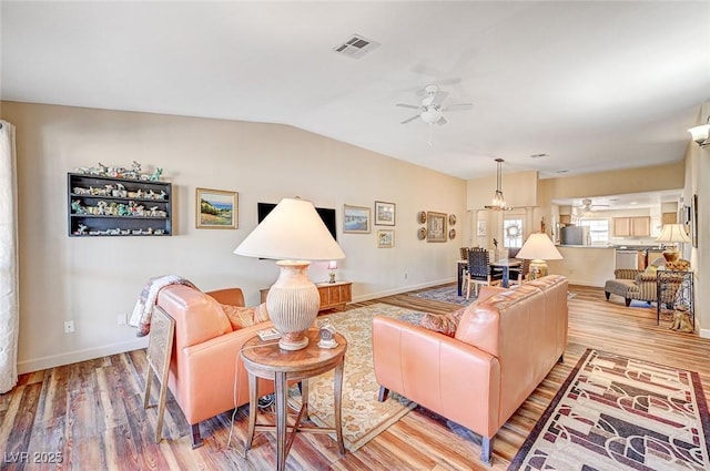 living room with ceiling fan, vaulted ceiling, and light wood-type flooring