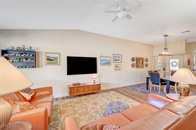 living room with lofted ceiling, ceiling fan with notable chandelier, and wood-type flooring