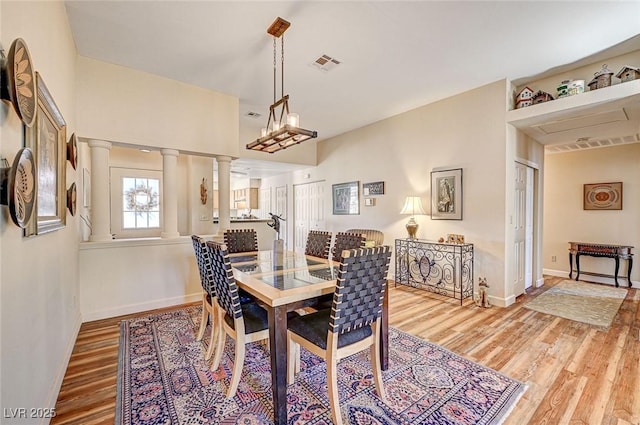 dining space featuring decorative columns and wood-type flooring