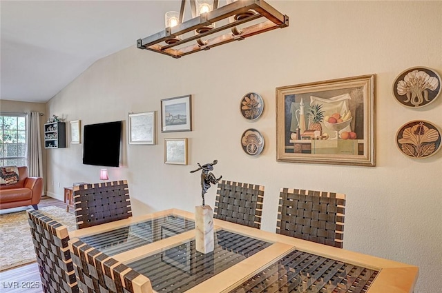 living room featuring an inviting chandelier, wood-type flooring, and vaulted ceiling