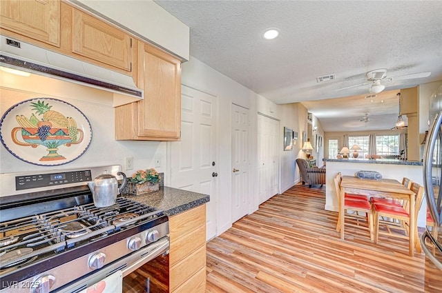 kitchen with gas stove, a textured ceiling, light brown cabinetry, and light hardwood / wood-style floors