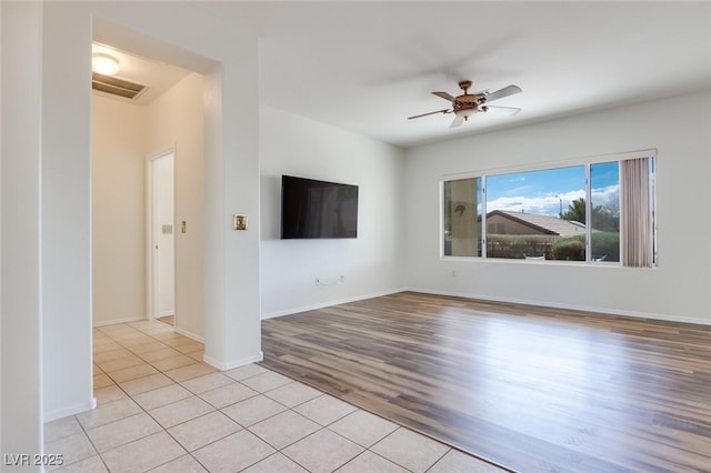 unfurnished living room with visible vents, light wood-style flooring, a ceiling fan, and baseboards