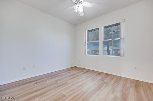 spare room featuring a ceiling fan, light wood-style flooring, and baseboards