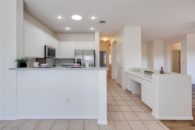 kitchen with stainless steel appliances, white cabinets, visible vents, and a peninsula