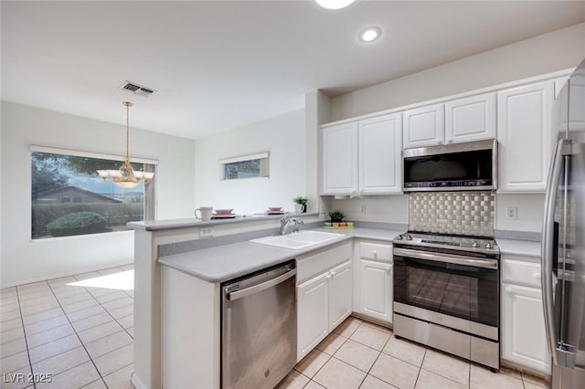 kitchen featuring a peninsula, appliances with stainless steel finishes, a sink, and white cabinetry