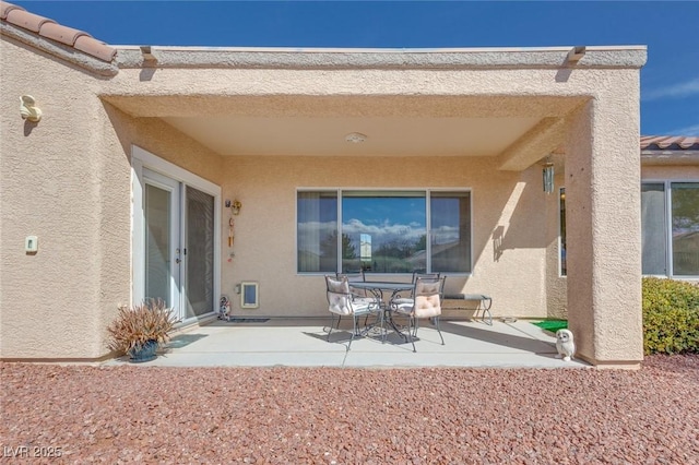 back of property with stucco siding and a patio