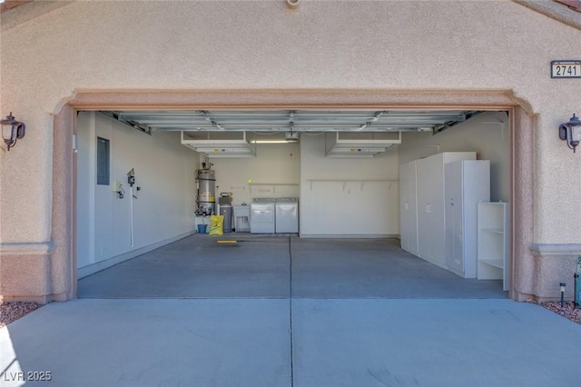 garage featuring strapped water heater, independent washer and dryer, and concrete driveway