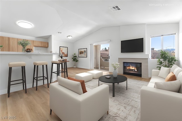 living room with vaulted ceiling, a healthy amount of sunlight, and light hardwood / wood-style floors