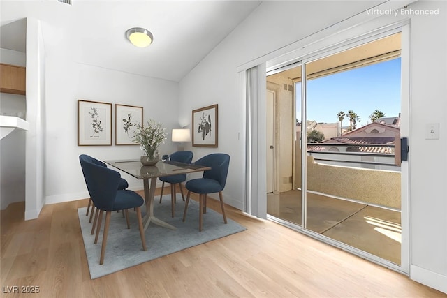 dining area featuring vaulted ceiling and light wood-type flooring