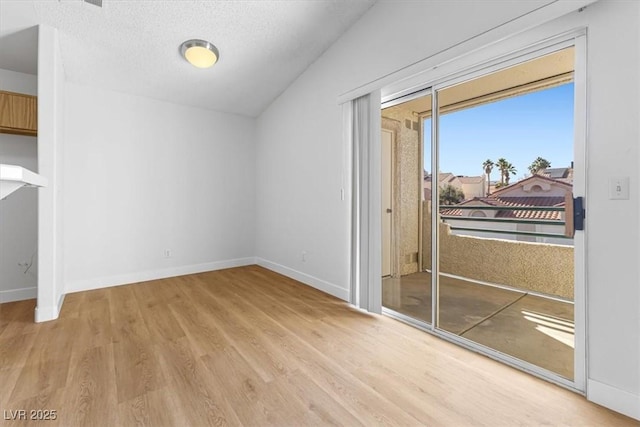 interior space with vaulted ceiling, light hardwood / wood-style floors, and a textured ceiling