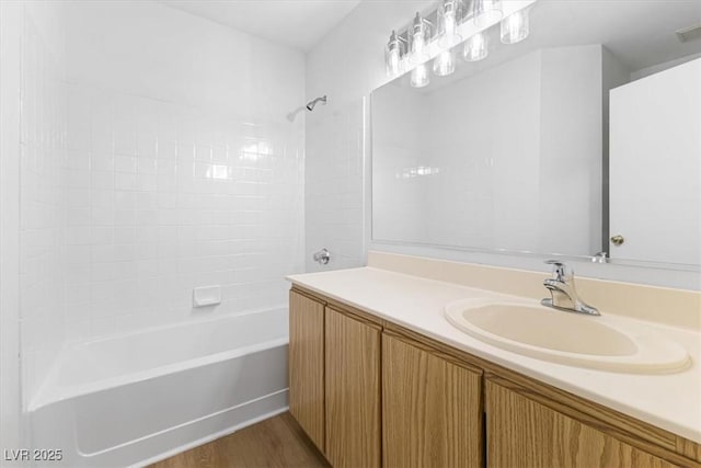 bathroom featuring hardwood / wood-style flooring, tiled shower / bath, and vanity